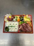 極上の黒毛和牛焼肉とお造り、フルーツ、煮物、豪華なお弁当です。