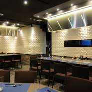 白い壁のタイルが印象的なシックな店内。鉄板焼きカウンターでは選び抜かれた食材を目の前で焼き上げます。神戸らしいオシャレな雰囲気のお店でワンランク上のひとときを演出します！