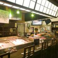 カウンター席に座ると目の前には、その日に獲れた旬の魚介類が並べられたケースとさまざまな銘酒が並べられた棚が。それらを眺めながら美味しい料理とお酒を味わうひとときは、まさに格別です。
