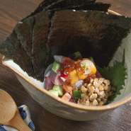 名前の由来は、細かくした魚介を納豆で練り混ぜたネタを火薬に見立てたことから。海苔で巻いてどうぞ！