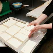 豆腐料理に使う「まめ力（りき）」は、姉妹店の工房で豆腐職人さんが毎日手づくりしています。素材は大豆・にがり・水だけ。シンプルだからこそ素材を厳選し、北海道と福岡の国産大豆、天然のにがりを使用。