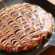 通常の10倍量の山芋と丁寧に刻んだキャベツが心地よい食感の『お好み焼き』。「出汁」は、鰹と昆布でとったものを使用しています。特製のソースとマヨネーズで見た目にも美しく仕上げた自慢の一品です。