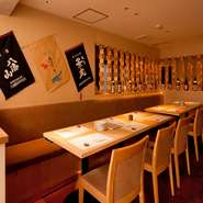 カウンターの後ろに並ぶテーブル席。壁には銘酒のボトルや米袋などが飾られ、新潟を感じさせてくれます。