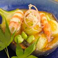 丸くくりぬいた賀茂なすと粟麩を素揚げにして冷やし、なすの外側部分を器に見立ててエビと茶豆を添えて盛り付けます。冷やしたポン酢のジュレとともにいただく、涼感あふれる季節の料理をお楽しみください。