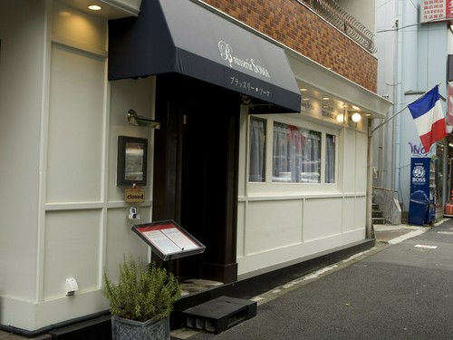 白い壁におしゃれな窓のカーテン、フランス国旗が印象的な外観