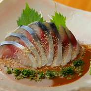 築地で厳選した新鮮な魚介を使った料理を、種類豊富に取り揃えております。今が旬のサバを使った『ごまサバ』は脂ののった身とゴマの風味がよく合う一品。すだちを絞った爽やかなタレでどうぞ。