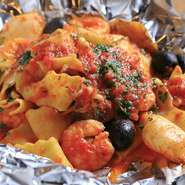 『魚介とオリーブ・ケイパーのトマトソース』は平打ちの自家製パスタと魚介をトマトソースで絡めた1品。アルミホイルで包んで蒸し焼きにし、そのままの状態で提供するので、開けた瞬間に魚介の香りが広がります。