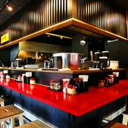 赤と黒に統一されたモダンな店内はカウンター席とテーブル席。一人でも気軽に座れるカウンターはお一人様にも人気となっています。