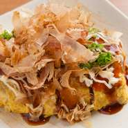和牛すじ肉を甘辛く時間をかけて柔らかくなるまで煮込み、そのままでも美味しいすじ肉を玉子に包み込んだ一品。ソースとマヨネーズ、その上にネギとたっぷりかつお節をのせ、あつあつできたてがおすすめです。