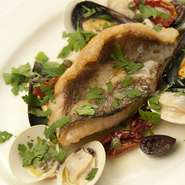 画像のメニューは「アクアパッツァ」。魚介類の旨味を焼いて閉じ込め、白ワインで香り高く仕上げた一品。