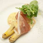 画像は、春野菜「ホワイトアスパラ」を使った料理の一例。素材の美味しさを、ダイレクトに味わっていただけます。「ホワイトアスパラ」を焼くことで甘みを閉じ込め、生ハムの塩分とソースでいただく一品。