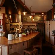 キッチンスペースを囲むV字のカウンターを中心に、ワインボトルに囲まれた店内は木の温もりあふれる気取らない雰囲気。女性でも男性でも、ふらりとひとりで訪れられる空気感に満ちています。