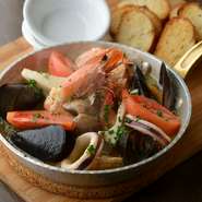 ニンニク風味がきいたオリーブオイルで魚介を煮込んだ一皿。ゲストの要望でつくられたメニューです。特製だしをいれたアヒージョ。是非、スープまで飲み干して欲しいです。