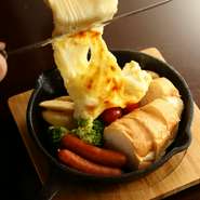 旬野菜・ソーセージ・パンが乗ったスキレットをテーブルにお持ちし、目の前で、とろ～り香ばしいラクレットチーズをかける演出を披露。香り・彩り・音が美味しさをアップし、SNS映えも◎。