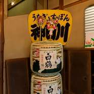 店名を刻んだ大きな団扇に白鶴の樽酒。店内には江戸前の心粋を感じられるインテリアが多彩です。