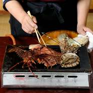 【海女料理ししくい】といえば名物『踊り焼き』。新鮮な活魚を熱々の鉄板で豪快に焼くパフォーマンスに、食べる方のテンションもアップ！　焼きあがるまでの時間も楽しむことができるので観光のお客様にもおすすめ。