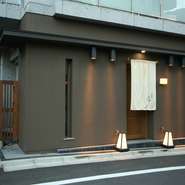 白金台の閑静な住宅街。隣接した植物園を背景にたたずむお店です。敷居をまたげば、木の温もりが漂う空間。板長と女将が、夫婦そろって出迎えてくれます。