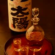 料理に合わせた日本酒や古酒をとり揃えています。アンティークな器が、お酒も料理も、ひきたてています。