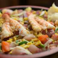 白身魚、サーモン、サバ、マグロなどの魚介をちらし、甘辛いうなぎのタレをかけた具だくさんの寿司。