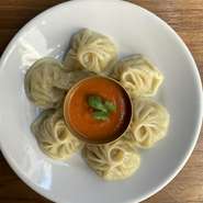 ネパール風の蒸し餃子。ゴマの香りとトマトの酸味が効いたオリジナルソースでお召し上がりください。