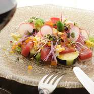 シェフ自らが毎朝市場に足を運んで厳選した魚介を使用しています。また、契約農家から直送した野菜も逸品。それらを贅沢に使った『本日の中央市場からの厳選カルパッチョといろいろ野菜のサラダ仕立て』が好評です。