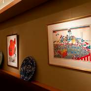 人気作家･田中正秋氏の華やかな祭りの版画が印象的な店内。器の棚を内装にきかせるなど斬新な空間づくり。