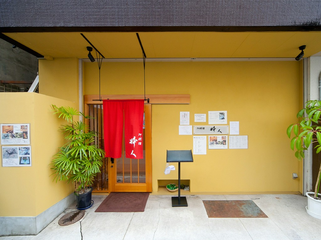 辛子色の壁に朱色の暖簾、店名にあるように粋な色合いの店頭です