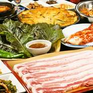 サムギョプサルとは韓国語で豚バラ肉のこと。斜めになっているテッパンの上で肉を焼いて脂を落とし、酸っぱいキムチをその脂で焼きます。焼いた肉はハサミでカット。サンチュで具材を巻いていただきます。