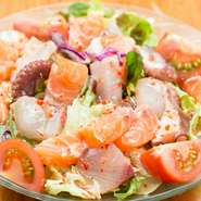 刺身としても食べられる新鮮な魚をどっさりと盛り込んだ、食べ応え満点のサラダです。酸味の効いたトマトとガーリック味のドレッシングで後を引く美味しさ。コストパフォーマンスが高く、女性に人気の逸品です。