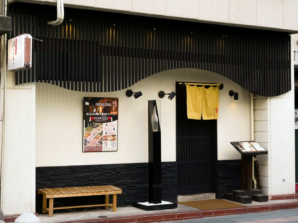 白い壁に黒の格子がモダンな外観。格子戸の先は落ち着いた和空間