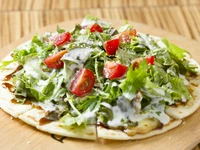 ピザ生地の上に鶏もも肉をのせ、チーズ、水菜、トマト、グリーンリーフ、サニーレタスなど、たっぷりの野菜とともにいただくヘルシーピザ。秘伝の照り焼きソースは甘みが強めで鶏肉によく合います。