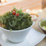 沖縄の在来豚「黒豚アグー」のほほ肉を特製ダレで一昼夜コトコト煮込み、地元の採れ立て食材「海ぶどう」と合わせた一品です。付け合せの手づくり『ジーマミ豆腐』はデザート感覚で楽しめます。