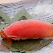 メバチ、キハダ、本マグロなど、旬の沖縄産の生マグロをお湯にくぐらせ「霜降り」にし、旨みを閉じ込めます。昆布だし、かつおだし、しょうゆ、酒、みりんで柵のまま漬けに。薄切りにした赤身の美しさにも大満足。