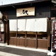 正面に掲げられた一枚板の看板は、どっしりと腰を据えた安定感を。風にはためく白い暖簾は緩やかな柔軟性を。濃いブラウン系を基調とした色合いは、落ち着きを醸し出しています。
