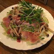 パルマ産高級生ハムとニンニクを効かせたきのこのマリネの食べごたえがあるサラダ。