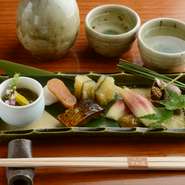 写真はコースのなかの『前菜盛り合わせ』。「つぶ貝」「にしんうま煮」「子持ち昆布」「もずく」など、旬素材をふんだんに使っています。ゆったりと楽しい食事の時間をお過ごしください。