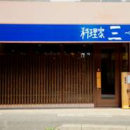 カウンターを作った杉の端材で作った大きくて目立つ看板が目印の当店。座敷もあり、落ち着いた雰囲気で、家にいるようにくつろげるのが自慢です。