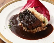 国産牛ホホ肉を香味野菜と赤ワインとともに一日寝かせ、ほほ肉に焦げ目をつけたあと特性ソースともに4～5時間、弱火でじっくりと煮込んだ逸品です。柔らかなホホ肉に風味豊かなソースが絡んでとても美味。