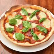 トマト・フレッシュバジル・モッツァレラチーズ・生ハムをのせた手打ちピッツァです。