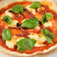 生地自体一からつくり上げた、確かな食感のこだわり自家製生地。そこにトマト・フレッシュバジル・モッツァレラチーズ・生ハムをのせています。