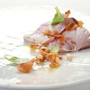 さっと湯引きした北海道産の鰤を、ポルチーニのムース、シャンピニンオンのチップスと松の実とともに。中華で使われる技を応用した紅麹のソースが独特のアクセントに。