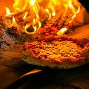 カウンターからほんの70cm先にパチパチと薪が燃える本窯が鎮座しており、カウンターからは一枚づつ丁寧に生地を伸ばしてピザをつくるすべての工程が見られます。本格ピザでカジュアルデートをお楽しみください。
