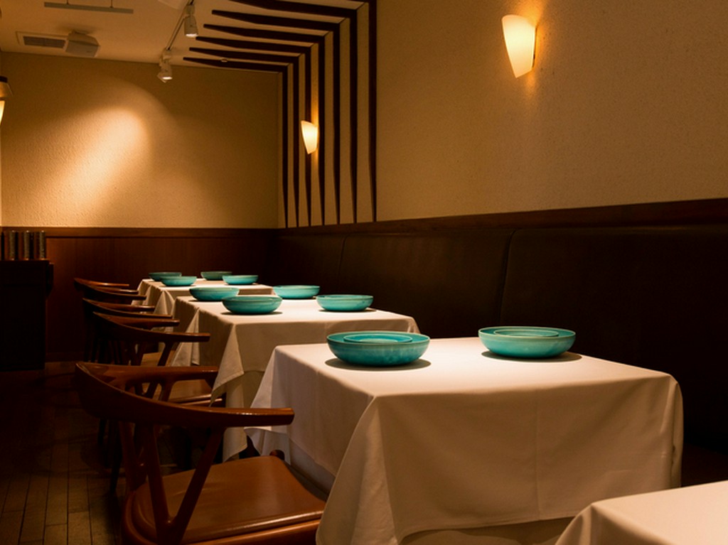 エメラルドグリーンの位置皿が浮かび上がるシンプルな空間