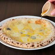 職人が手で伸ばしたピッツァ生地に、4種類のチーズをのせて焼いた『クワトロフォルマッジ』はナポリピザの定番。これに蜂蜜がプラスされ、チーズの塩気と蜂蜜の甘さで、さらに新しいおいしさを生み出しています。