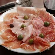 生ハムとサラミ、モルタデッラソーセージの盛り合わせ。中でも世界三大ハムのひとつ『パルマ産　生ハム』の、絶妙な塩気とコクのある旨みは格別です。「ハウスワインと合わせ、気楽に食べていただきたい」とのこと。