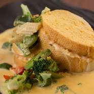 プリプリの海老をバケットで挟み、オーブンでカリッと香ばしく焼き上げます。ウニクリームソースが濃厚な味わい、ソースがしみたパンも絶品です。ボイルした野菜がアクセント。女性に人気のメニューです。