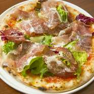 マルゲリータベースのナポリ風本格ピッツァ。旬の野菜や生ハムを贅沢に乗せた、スペシャルトッピングがうれしいメニューです。400度の窯で一気に焼き上げるため、モチモチとした生地の風味も楽しむことができます。