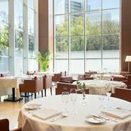 手入れが行き届いたカトラリーや清潔なクロスが眩しいテーブル席。スタッフのスマートな所作からは、洗練された雰囲気が漂います。昼は壁一面を切り取る大きな窓から柔らかな陽射しが降り注ぎ、優雅な時間をお約束。