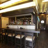 ダークな色合いのフローリングにイスとテーブル。オレンジ色の照明が明るすぎず暗すぎず照らし出す落ち着いた店内はデートに最適です。女性が喜ぶ低カロリー高たんぱくな魚介料理と各地の銘酒で素敵なひとときを。