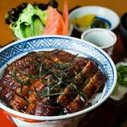 ご飯の上にウナギの蒲焼きを盛りつけた名物丼です。蒲焼きにはすっきりした秘伝のタレがよく染みこみますが、ワサビ醤油と刻みネギをかけてお召し上がり下さい。ウナギの下に隠れる大葉もいいアクセントです。